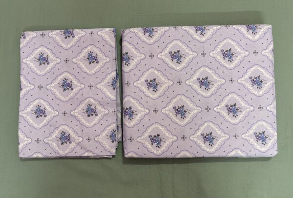 Lavender printed cotton bedsheet set on wooden bed with matching pillow covers