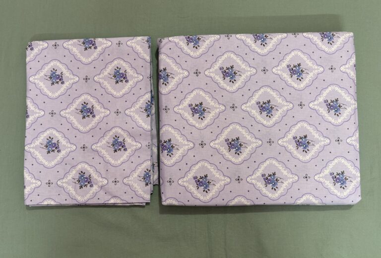 Lavender printed cotton bedsheet set on wooden bed with matching pillow covers