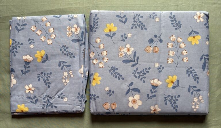 Dusty blue floral print cotton bedsheet set on wooden bed with matching pillow covers